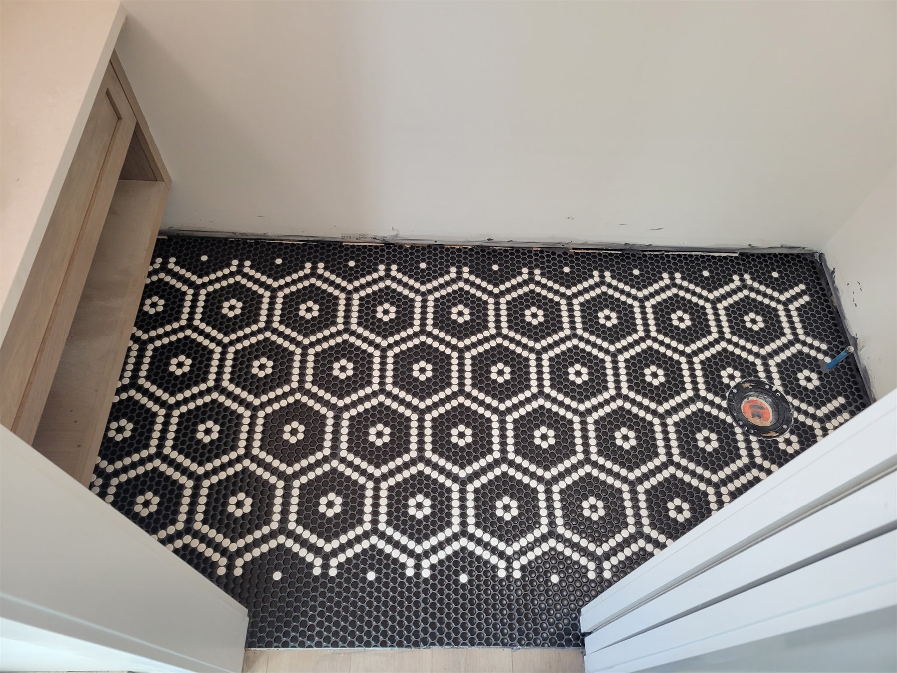 Custom black and white penny tile floor assembled in a hand-built pattern